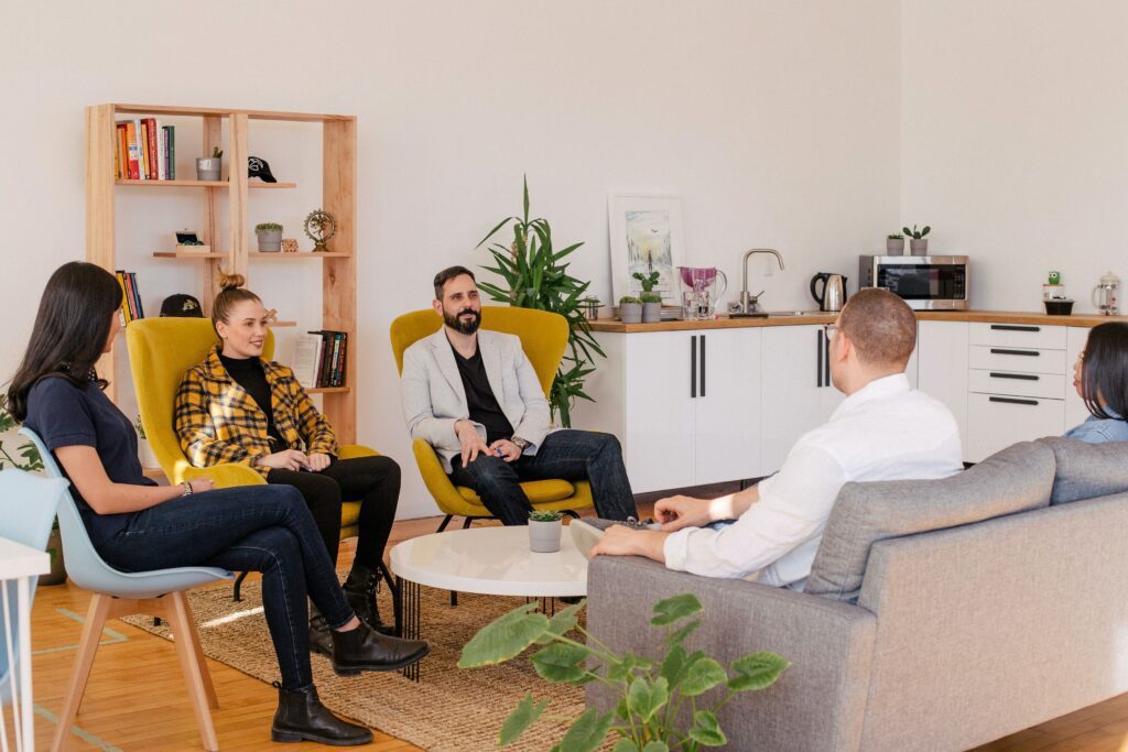 Persone riunite in una sessione di coaching aziendale comodamente sedute su divani e poltrone da ufficio