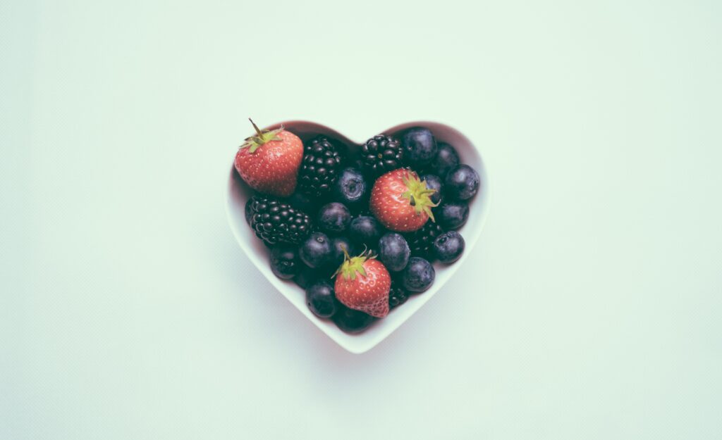Ciotolina a forma di cuore che contiene bacche e frutti rossi