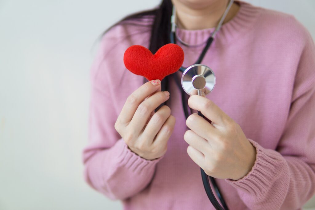 Una donna che indossa uno stetoscopio che mantiene un cuore rosso di stoffa